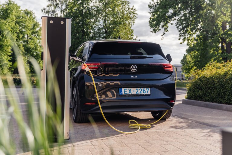 Czarny samochód elektryczny Volkswagen ID.3 ładuje się na stacji ładowania na zewnątrz w słoneczny dzień.