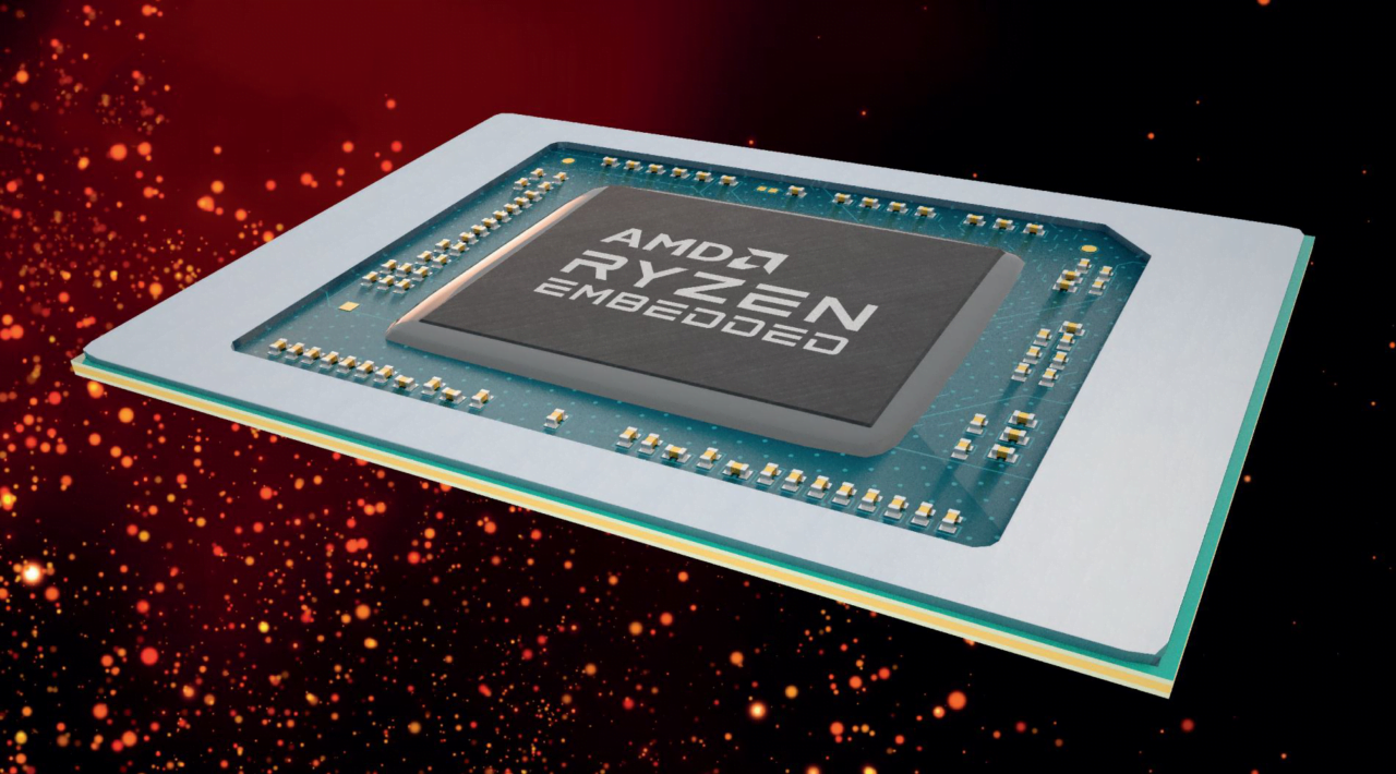 Procesor AMD Ryzen Embedded na płytce z widocznymi pinami, umieszczony na tle z rozmytymi światełkami.