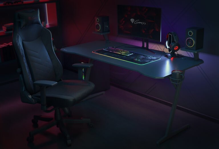 Ustawienie gamingowe z podświetlonym biurkiem, komputerowym fotelem, klawiaturą, myszą, dwoma głośnikami i monitor z logo firmy na ciemnym tle. Biurko do pracy, ale i do gier