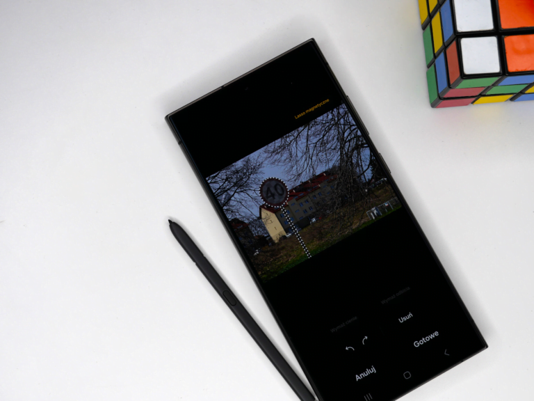 Tablet z wyświetlonym zdjęciem wieży z zegarem na ekranie edycji obrazu, obok leży stylus, a w górnym rogu zdjęcia widoczny jest fragment kostki Rubika.