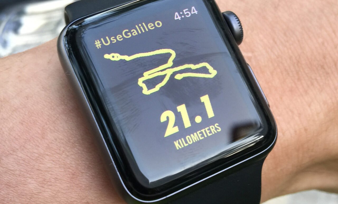 Inteligentny zegarek na nadgarstku wyświetlający trasę biegu, czas 4:54, hashtag #UseGalileo oraz odległość 21.1 kilometrów.