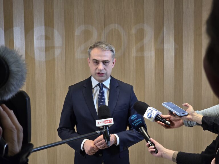 SECURE 2024, Minister Cyfryzacji Krzysztof Gawkowski. Mężczyzna w garniturze udzielający wywiadu grupie dziennikarzy, mikrofony skierowane w jego stronę.