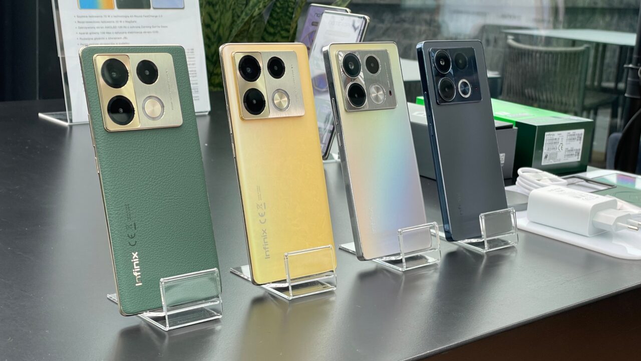 Różnokolorowe smartfony Infinix z potrójnymi aparatami fotograficznymi, wystawione na stojakach w sklepie.
