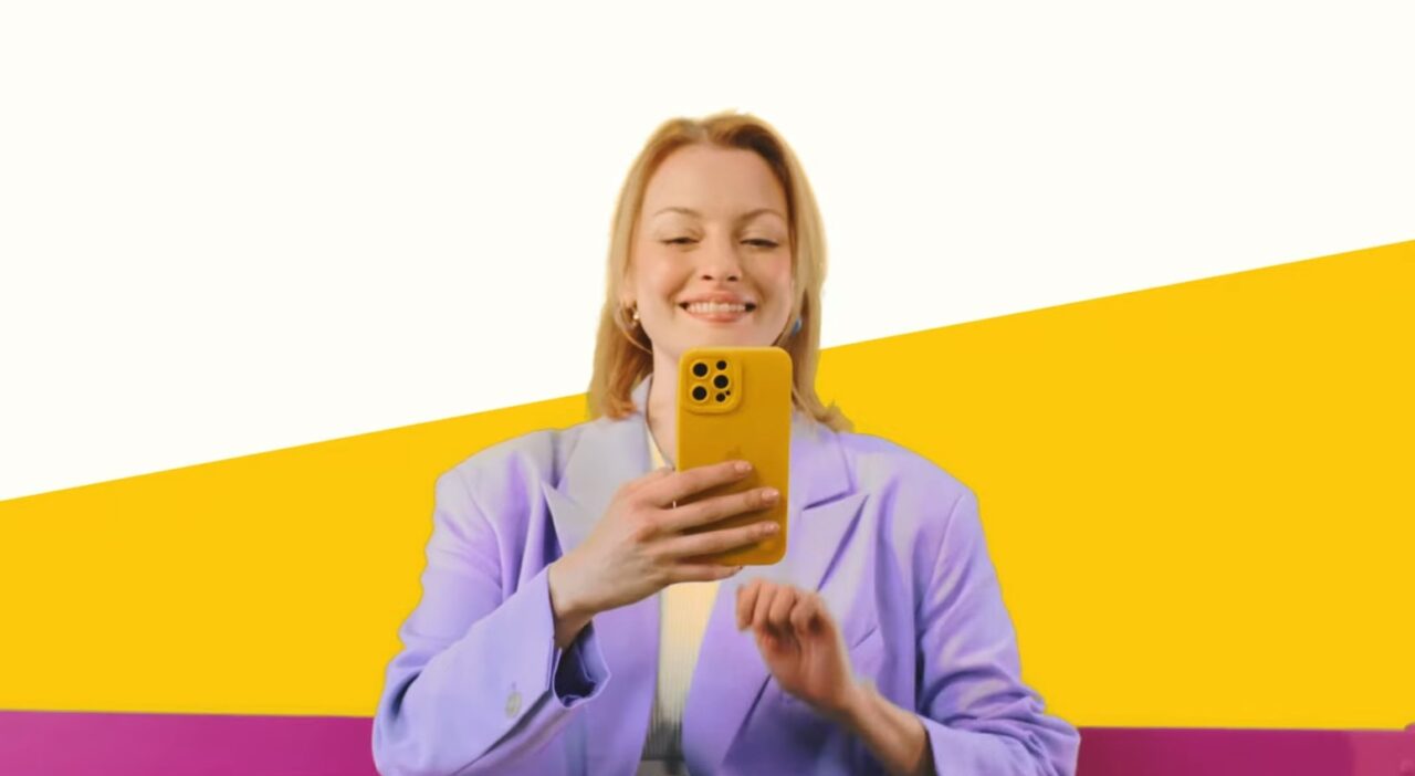 Uśmiechnięta kobieta trzymająca smartfon w żółtym etui