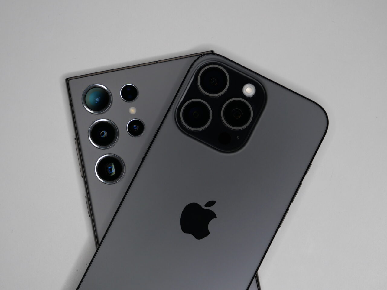 Dois smartphones sobre um fundo branco, com câmeras traseiras e o logotipo da Apple visível.