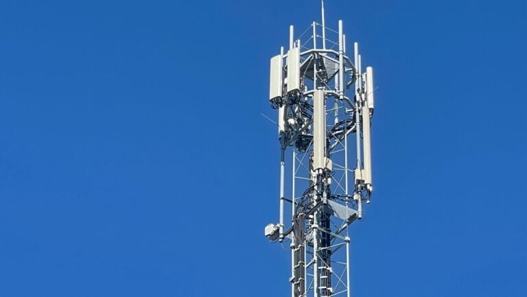 Maszt telekomunikacyjny z antenami na tle niebieskiego nieba.