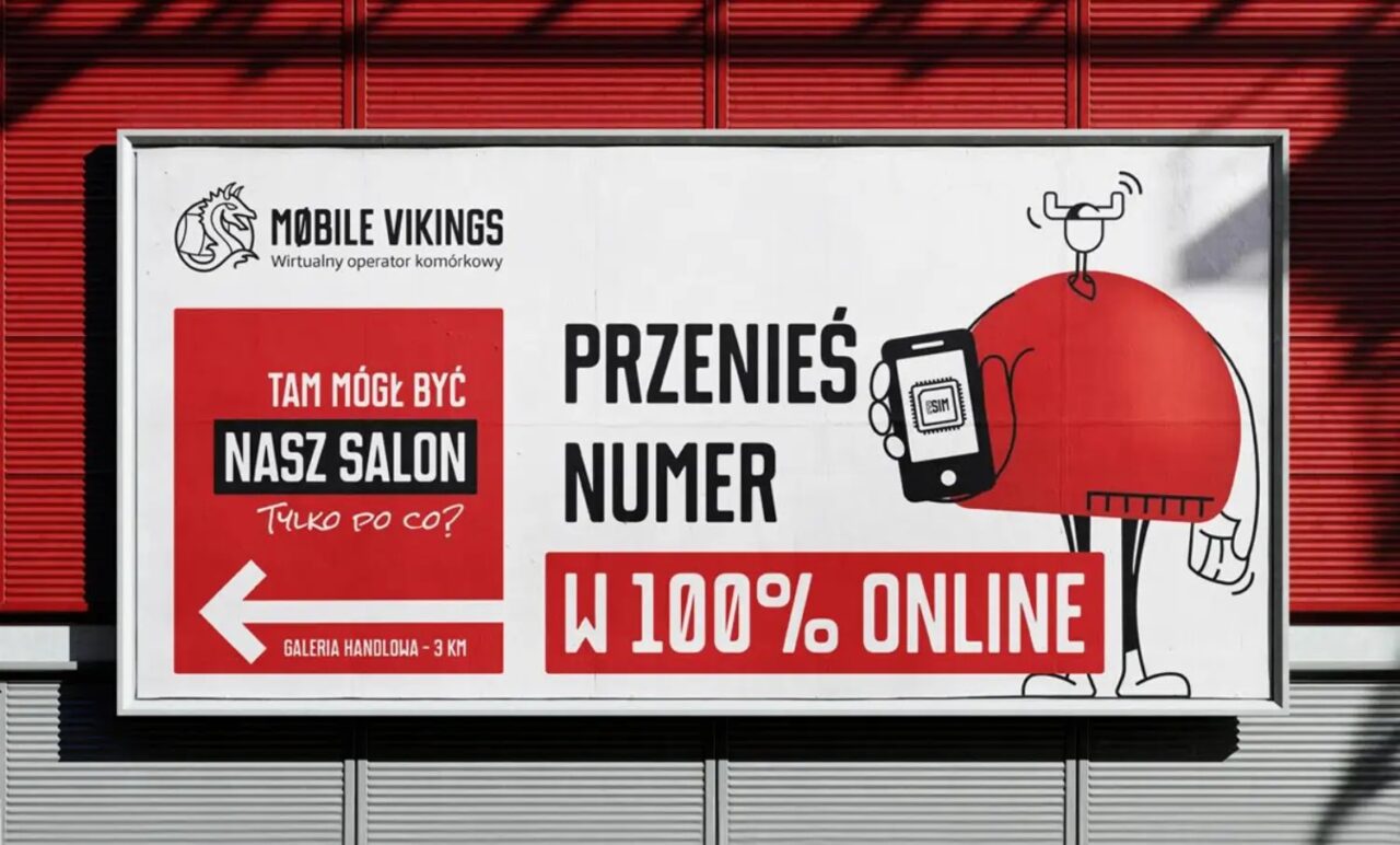 Billboard reklamowy Mobile Vikings z grafiką komórki z eSIM w dłoni postaci kreskówkowej i tekstem promującym przenoszenie numeru przez internet.