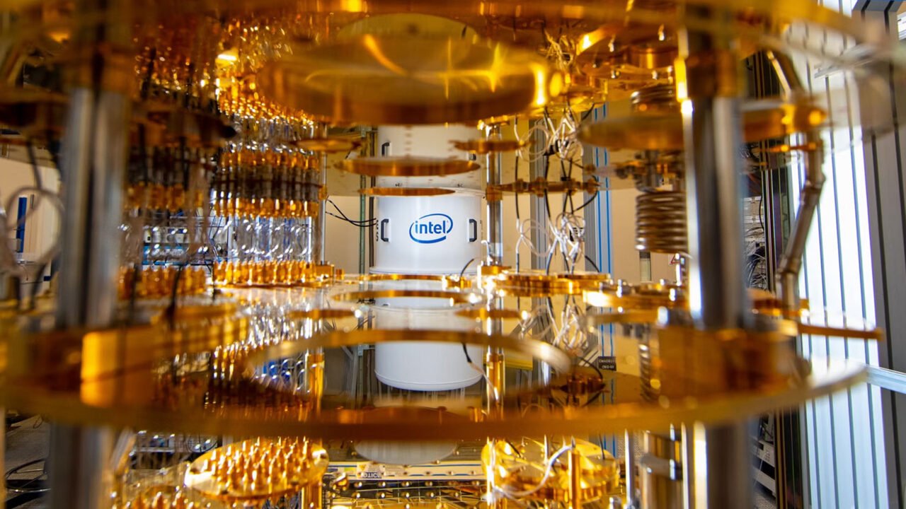 Komputery kwantowe. Jednostka z logo firmy Intel widocznym w centrum. Jest ono otoczone przez złote i metaliczne komponenty urządzenia.