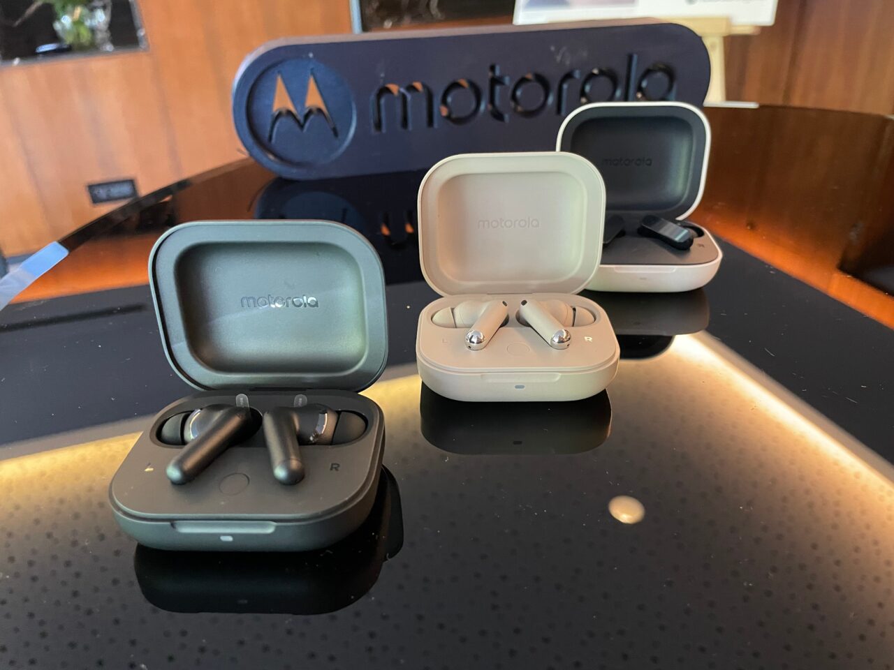 Zestawy słuchawkowe Motorola umieszczone na ciemnym blacie przy otwartych ładowarkach.