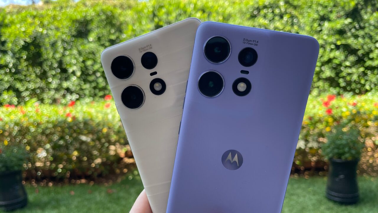 Dwa smartfony trzymane w dłoni na tle zielonego ogrodu, jeden biały i jeden fioletowy, z widocznymi układami wielu aparatów fotograficznych.