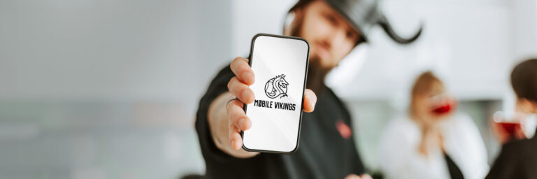 Mężczyzna pokazuje ekran smartfona z logo "Mobile Vikings"