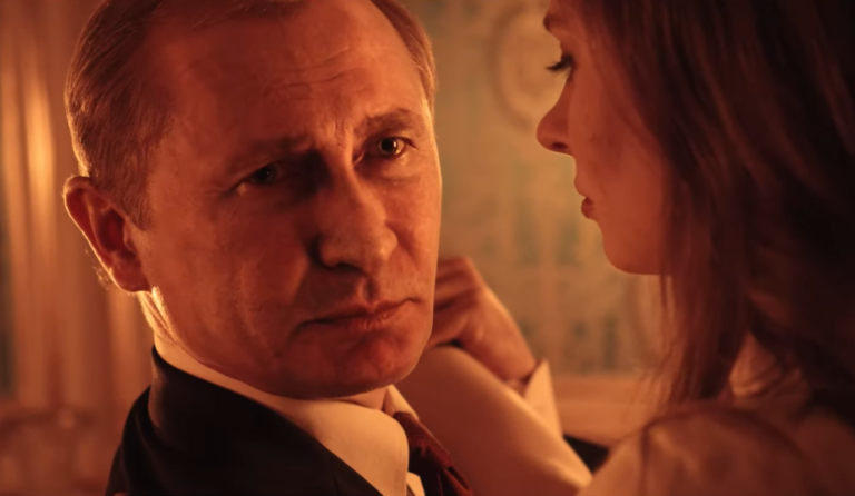Putin w czarnym garniturze patrzy intensywnie na twarz kobiety w złotej sukience, w ciepłym, pomarańczowym świetle.