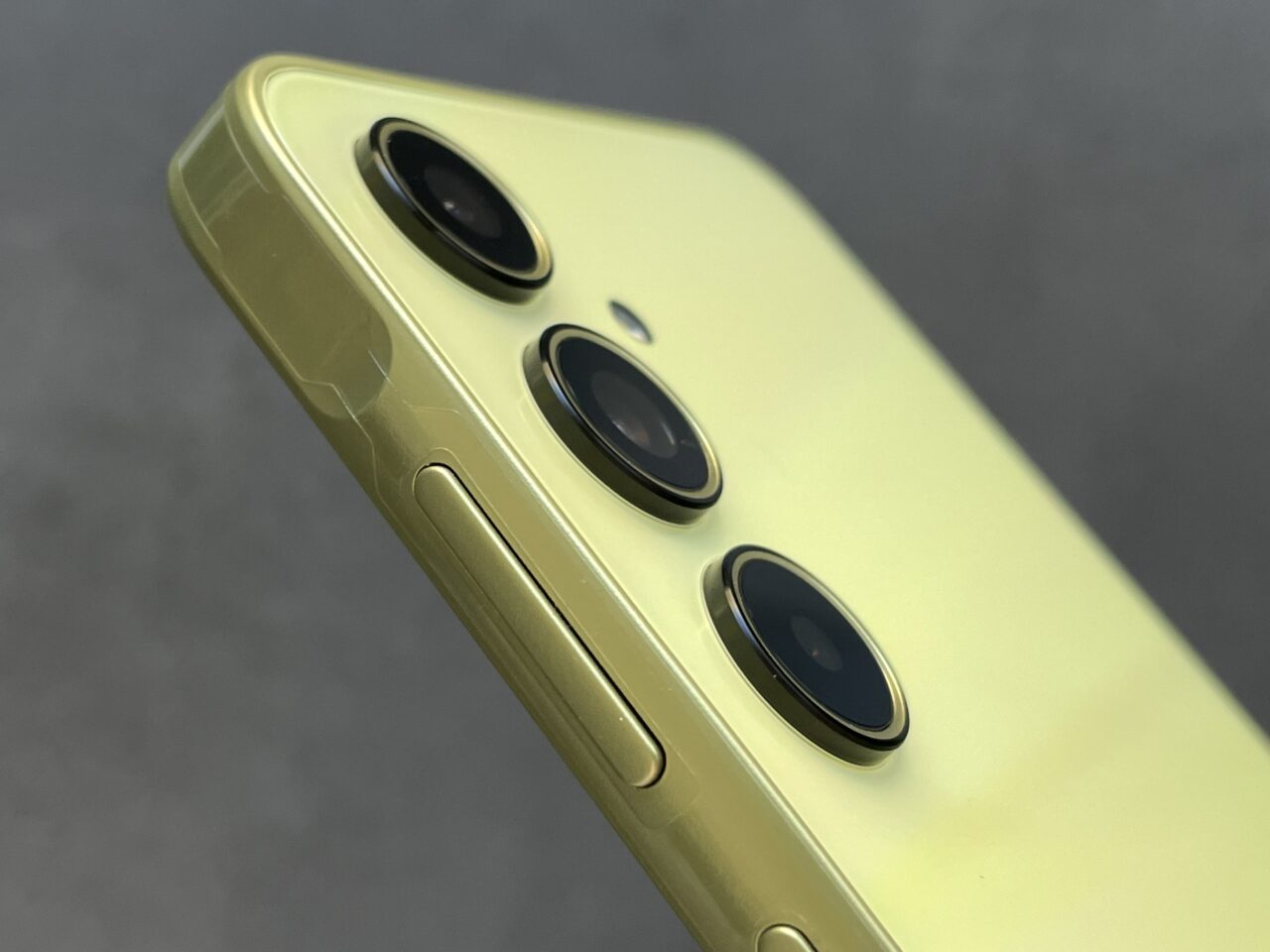 Żółty smartfon z potrójnym aparatem i przyciskiem bocznym.