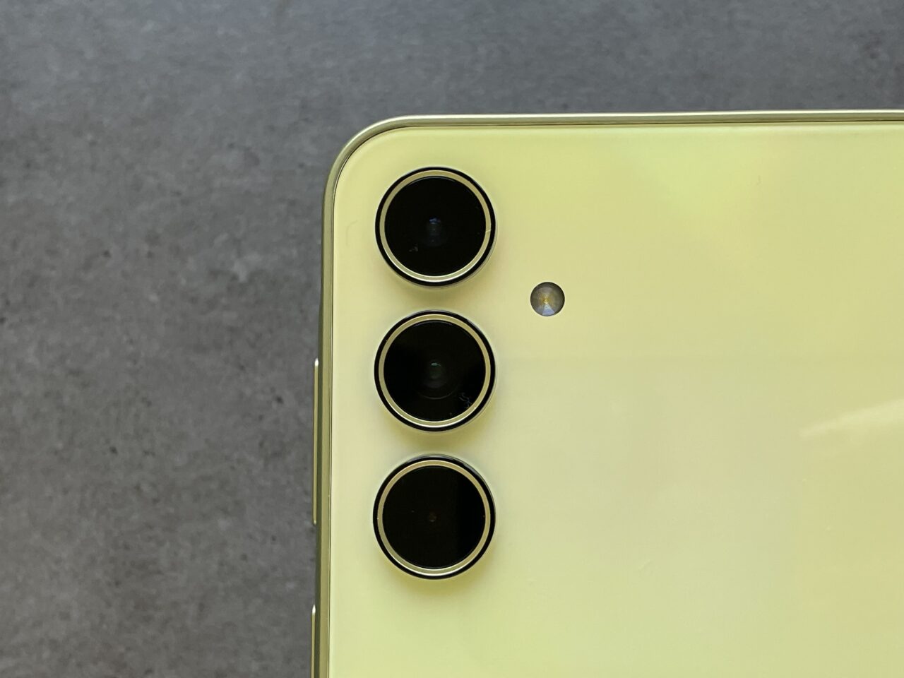 Tylna część żółtego smartfona z trzema obiektywami aparatu i błyskiem LED.