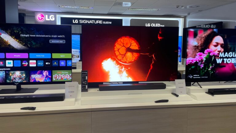 Ekspozycja telewizorów LG w sklepie elektronicznym, z różnymi materiałami wideo na ekranach.