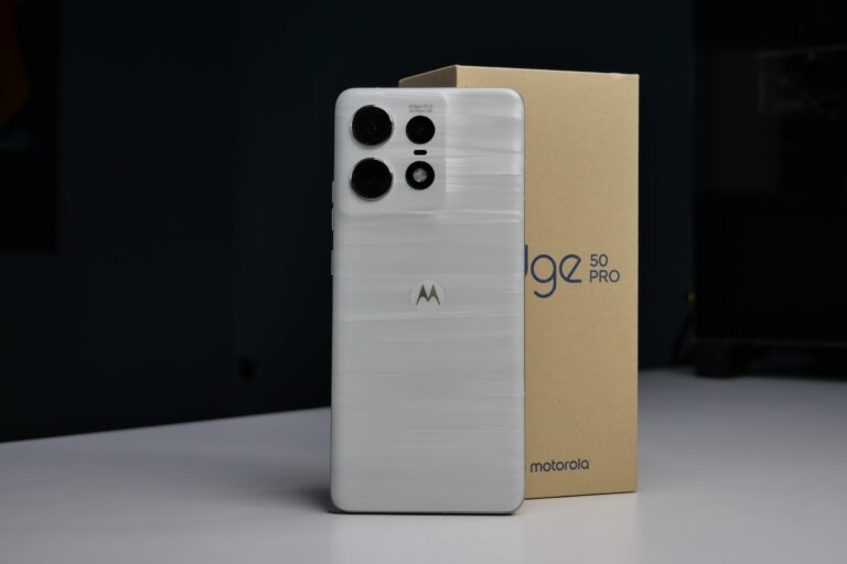 Biały smartfon Motorola z potrójnym aparatem obok pudełka z napisem Edge 50 Pro.