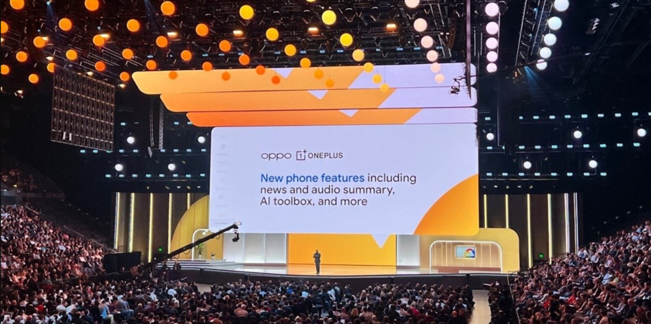 Prezentacja na dużym ekranie podczas konferencji z widownią i prelegentem na scenie, na ekranie znajduje się logo OPPO i OnePlus oraz opis nowych funkcji telefonu.