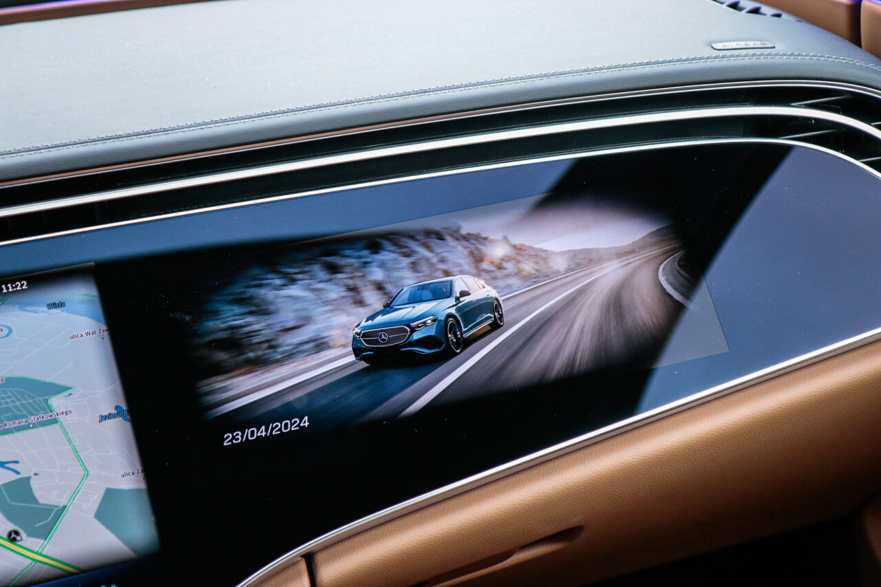 Ekran Superscreen w testowanym Mercedesie klasy E wyświetlający obraz jadącego samochodu na zimowej drodze.