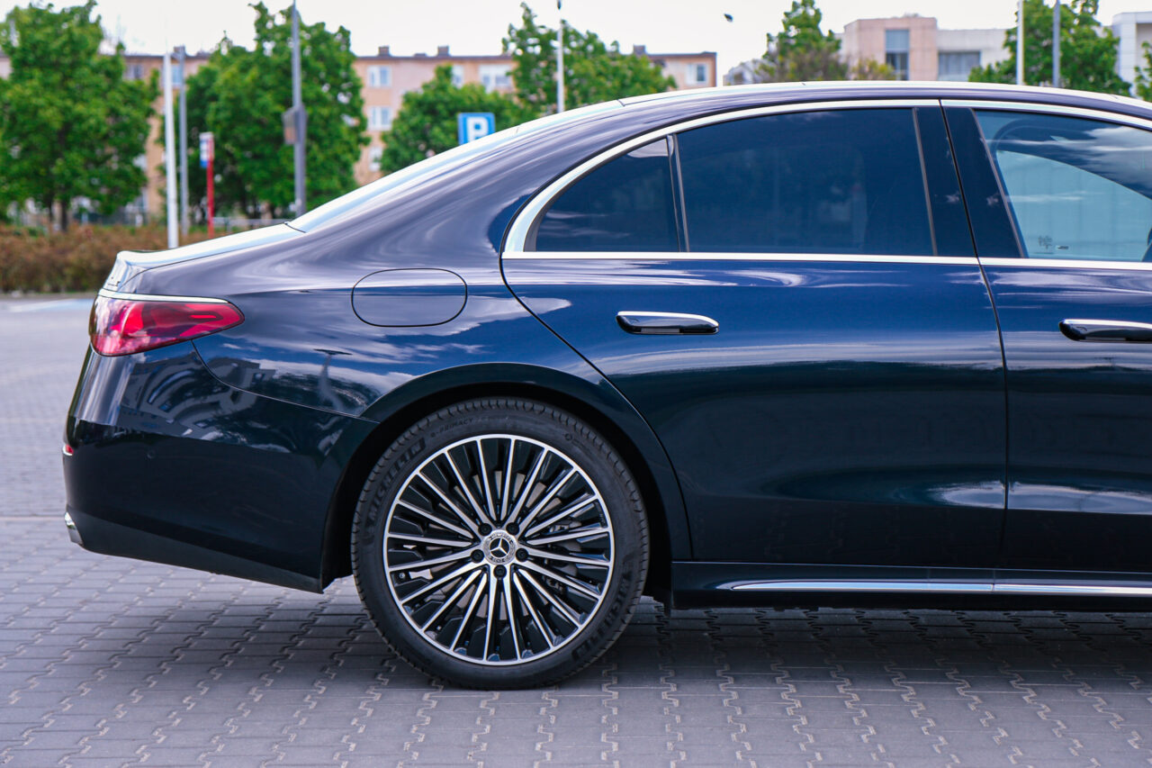 Test Mercedesa Klasy E zaparkowany na miejskim parkingu, boczny widok prezentujący eleganckie detale i charakterystyczne felgi.