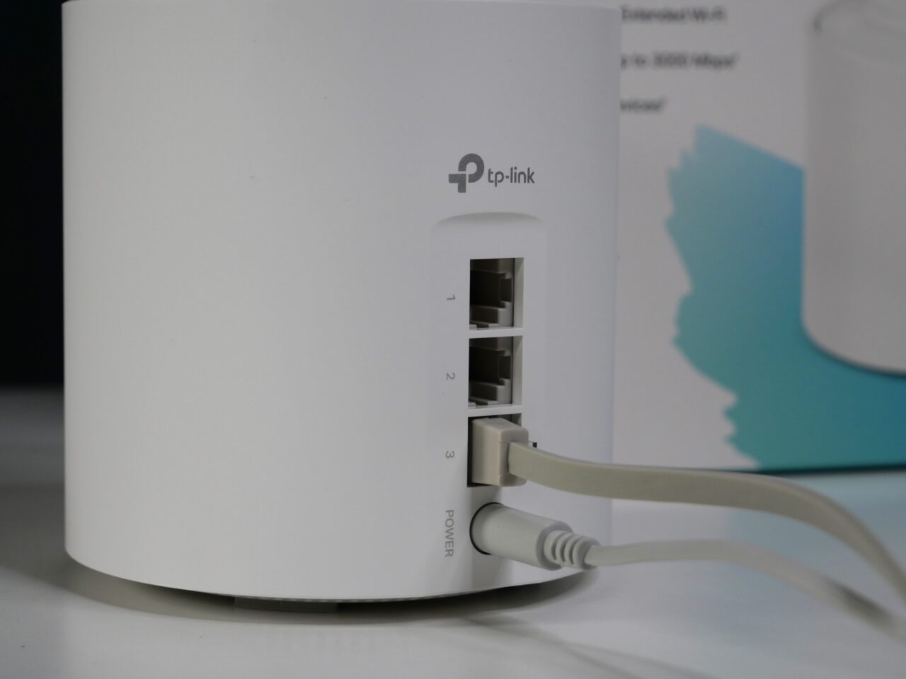 Biały router TP-Link z podłączonym kablem Ethernet w przybliżonym widoku z lekkim rozmyciem tła.