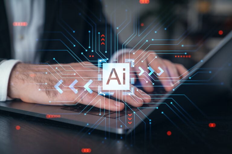 Mężczyzna używający laptopa z holograficznymi elementami graficznymi symbolizującymi sztuczną inteligencję (AI) na pierwszym planie.