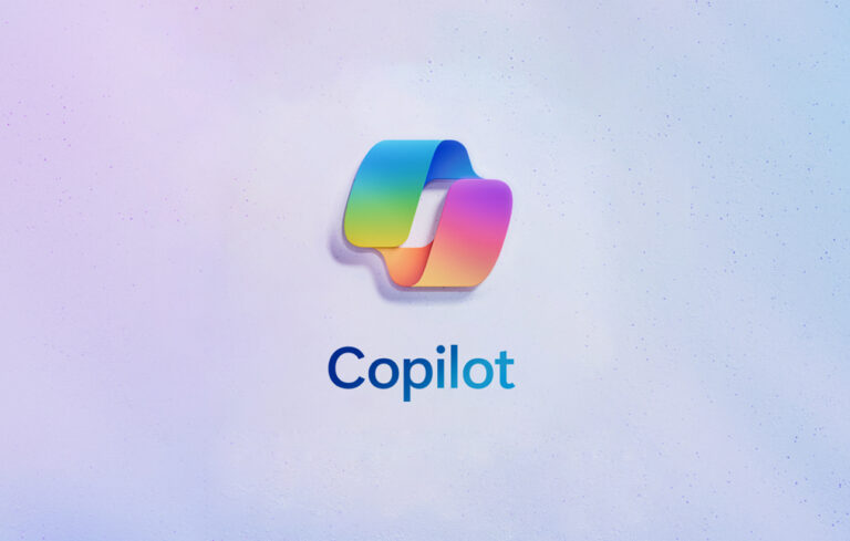 Logo "Copilot" w kształcie trójwymiarowej nieregularnej bryły z gradientem kolorów, na tle z fakturą przypominającą drobny piasek.