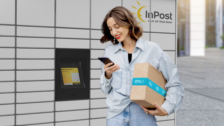 Kobieta używa telefonu komórkowego, odbierając paczkę z paczkomatu InPost.