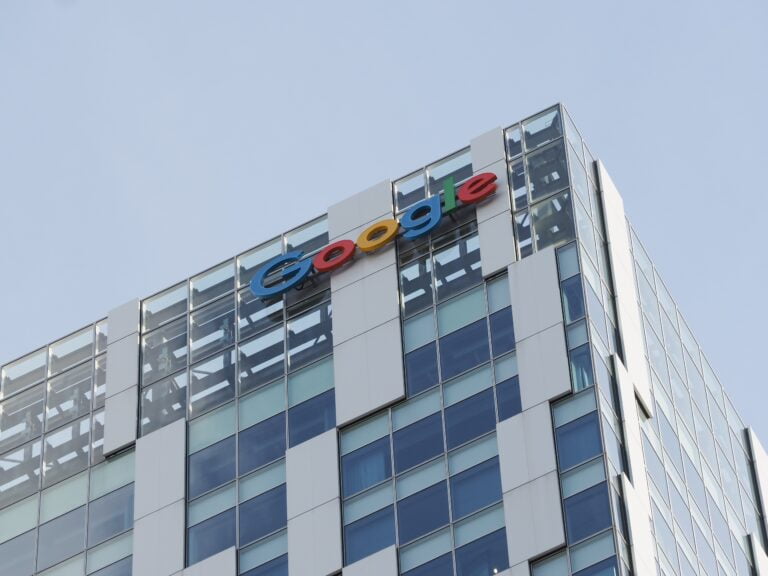 Tablica z logo Google na szklanym wieżowcu.