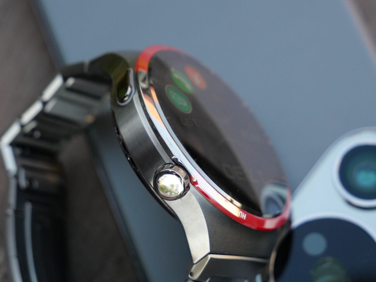 Zbliżenie na smartwatch z metalową bransoletą oraz smartfon z widocznymi aparatami.