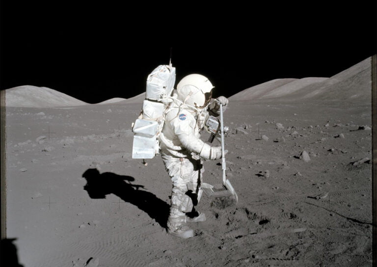 Astronauta na Księżycu wykonuje pomiary z użyciem specjalistycznego sprzętu, w tle krater i góry księżycowe.