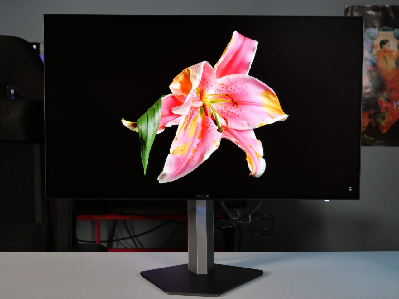 Monitor na biurku wyświetlający obraz kwiatu lilii.