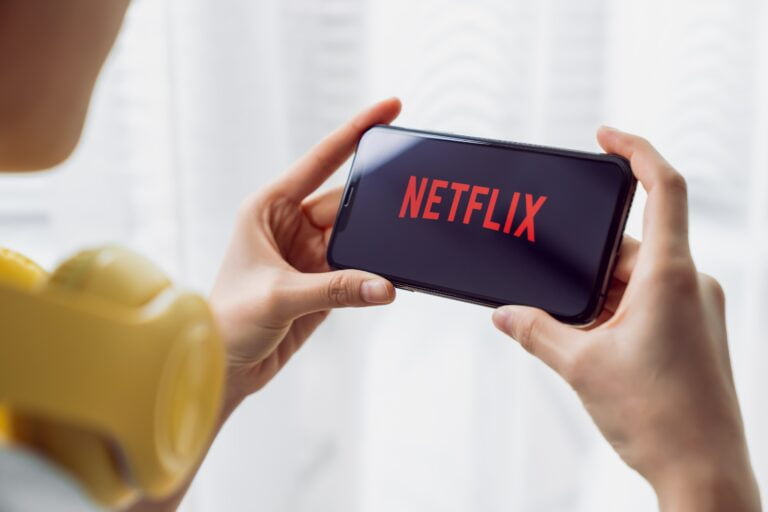 Osoba trzymająca smartfona z logiem Netflix na ekranie.