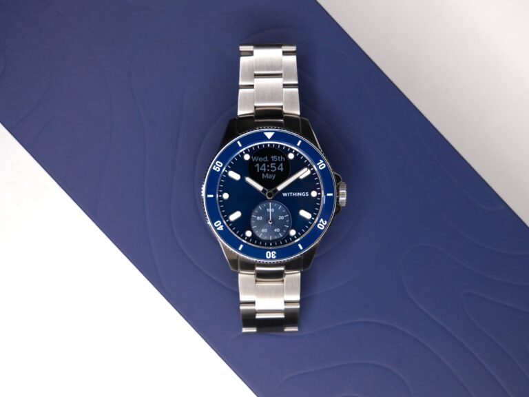 Zegarek Withings z niebieską tarczą i srebrną bransoletą na niebieskim tle.