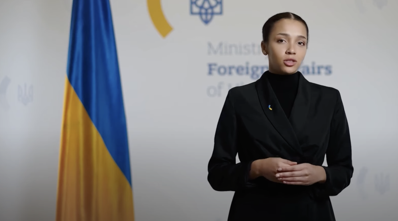 Victoria Shi - nowa rzeczniczka Ukrainy. Młoda kobieta w czarnym garniturze stoi przed flagą Ukrainy i logotypem Ministerstwa Spraw Zagranicznych Ukrainy.