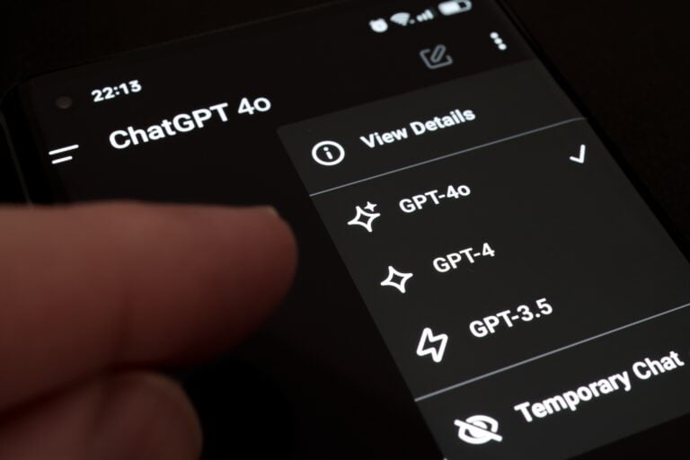 Ekran telefonu z aplikacją ChatGPT, menu wyboru modeli GPT (GPT-4o, GPT-4, GPT-3.5) i palec wskazujący.