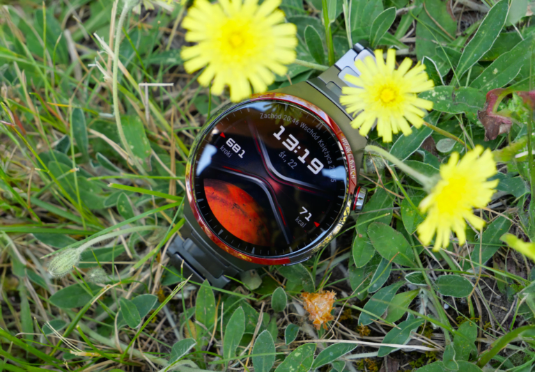 Smartwatch Huawei Watch 4 Pro leżący na trawie przy żółtych kwiatach