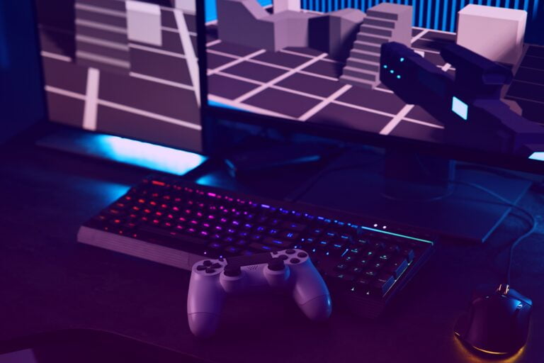 Stacja do gier z podświetlaną klawiaturą, białym kontrolerem do gier i wyświetlaczem z grafiką 3D w oświetleniu neonowym.