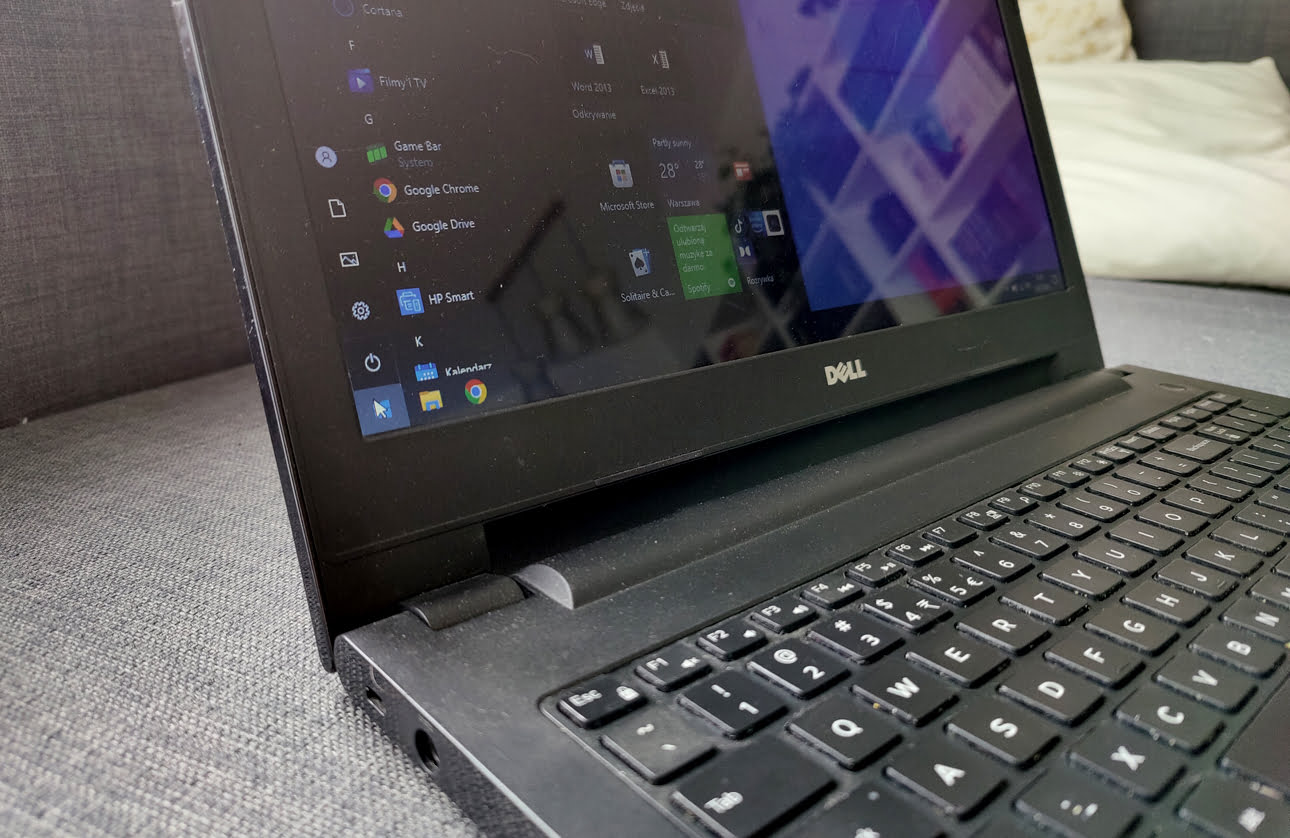 Laptop Dell z uruchomionym systemem Windows, widok z boku na ekran i klawiaturę.