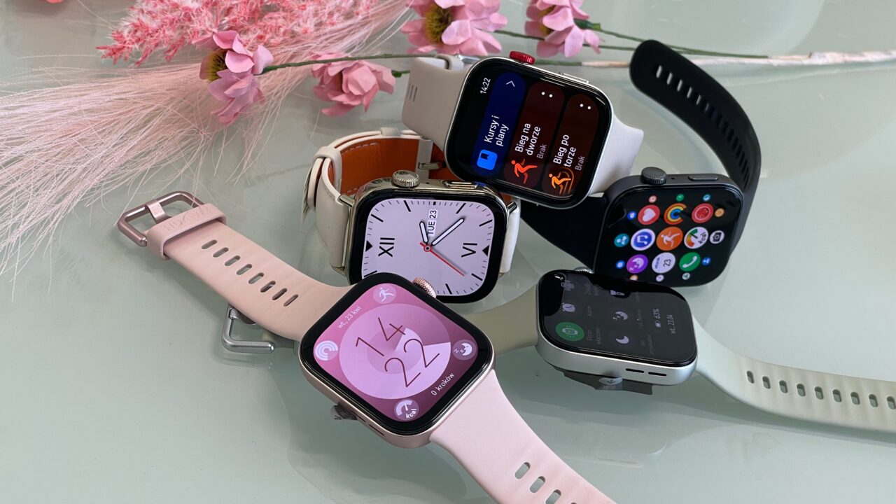Huawei Watch Fit 3. Kolekcja różnych smartwatchy na szklanym stole z kwiatami w tle.