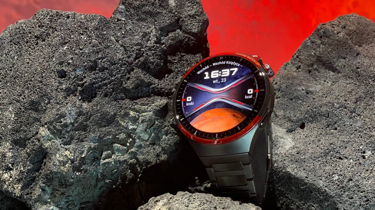 Inteligentny zegarek Huawei Watch 4 Pro Space Edition na czarnych wulkanicznych skałach z czerwonym tłem przypominającym lawę.