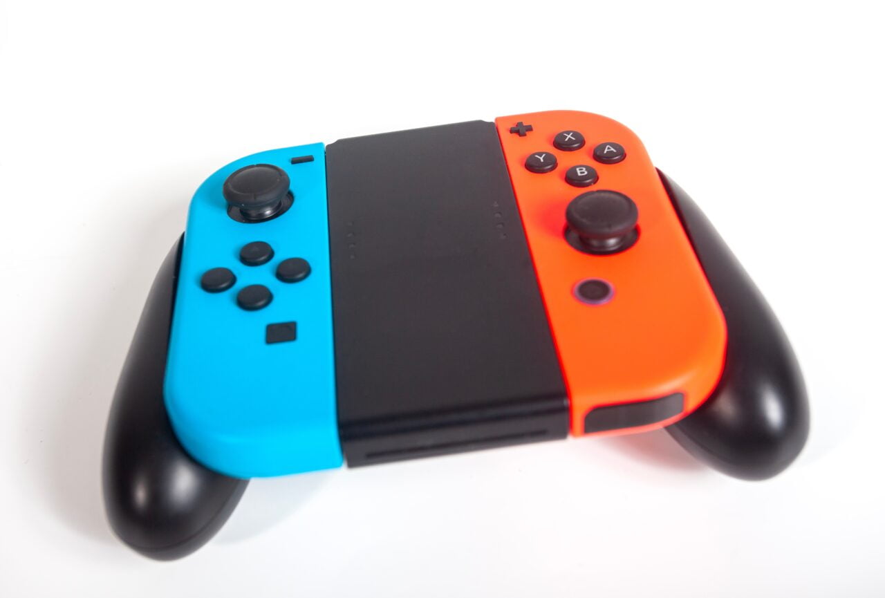 Kontroler do gier dla Nintendo Switch z niebieskim i pomarańczowym przyciskiem na białym tle.