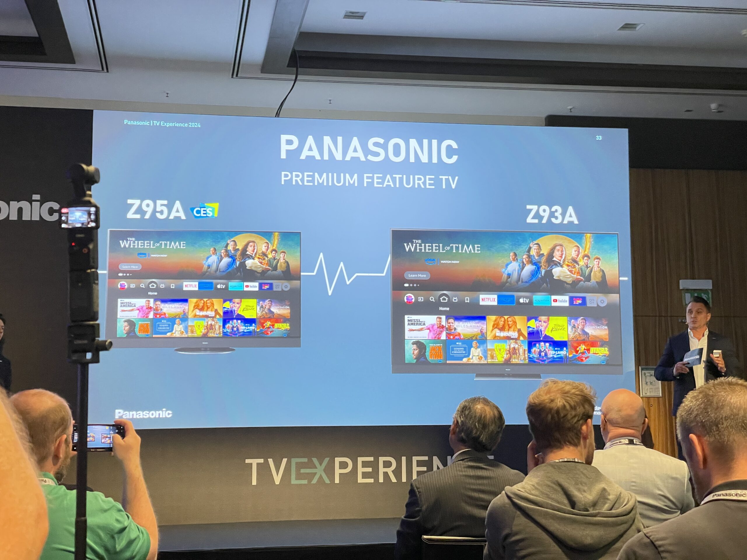 Pessoas na apresentação das TVs Panasonic Z95A e Z93A, com telas iniciais e aplicativos exibidos.