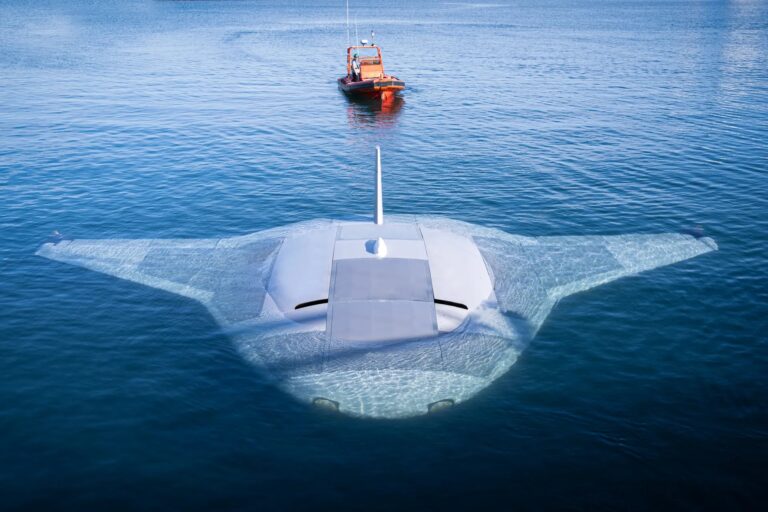 manta ray Podwodny pojazd w kształcie płetwy rekina na powierzchni wody, z łodzią ratunkową w tle.