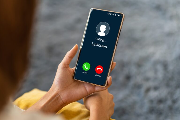 Osoba trzyma telefon, na ekranie wyświetla się połączenie od nieznanego numeru z opcjami "Akceptuj" i "Odrzuć".