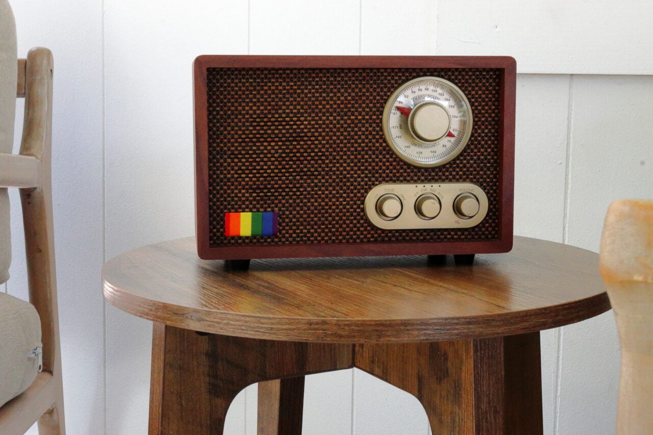 Brązowe, vintage radio z dużą gałką i trzema mniejszymi, stojące na drewnianym stoliku.