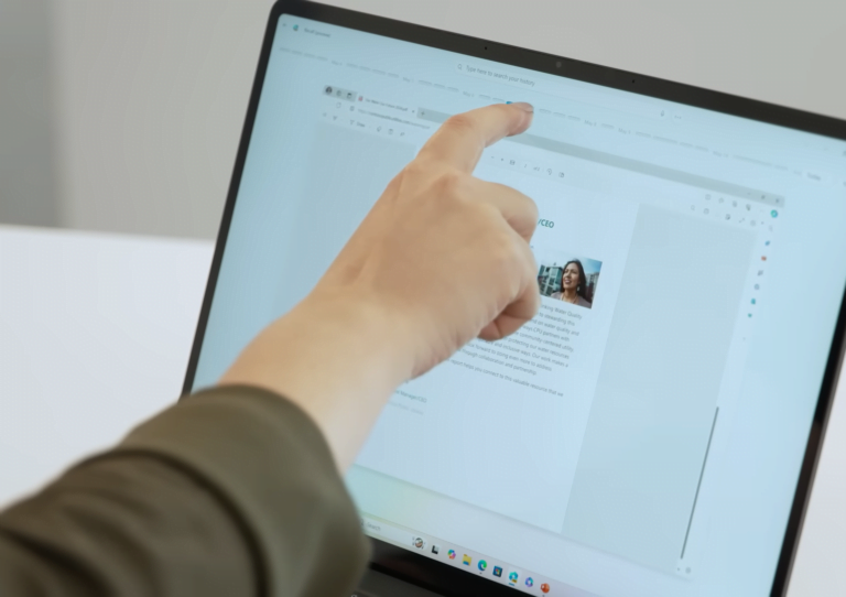 Osoba wskazująca palcem na ekran dotykowy laptopa pracując z funkcją Recall na systemie Windows 11.