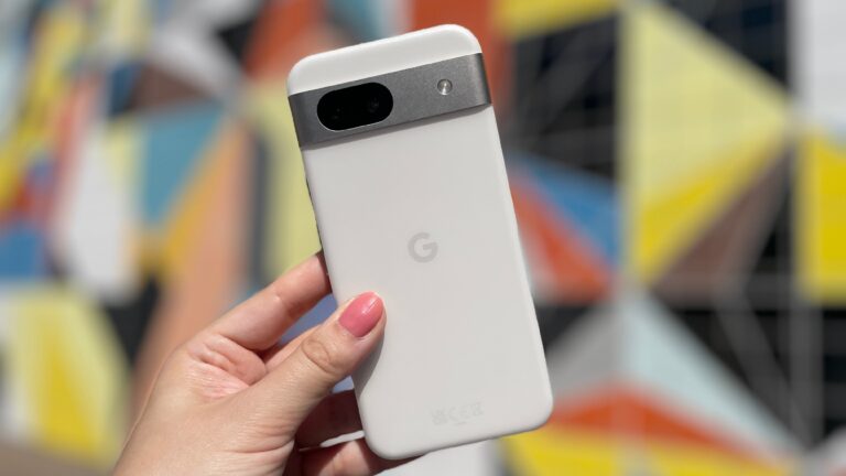 Osoba trzymająca biały telefon Google Pixel przed kolorowym tłem.