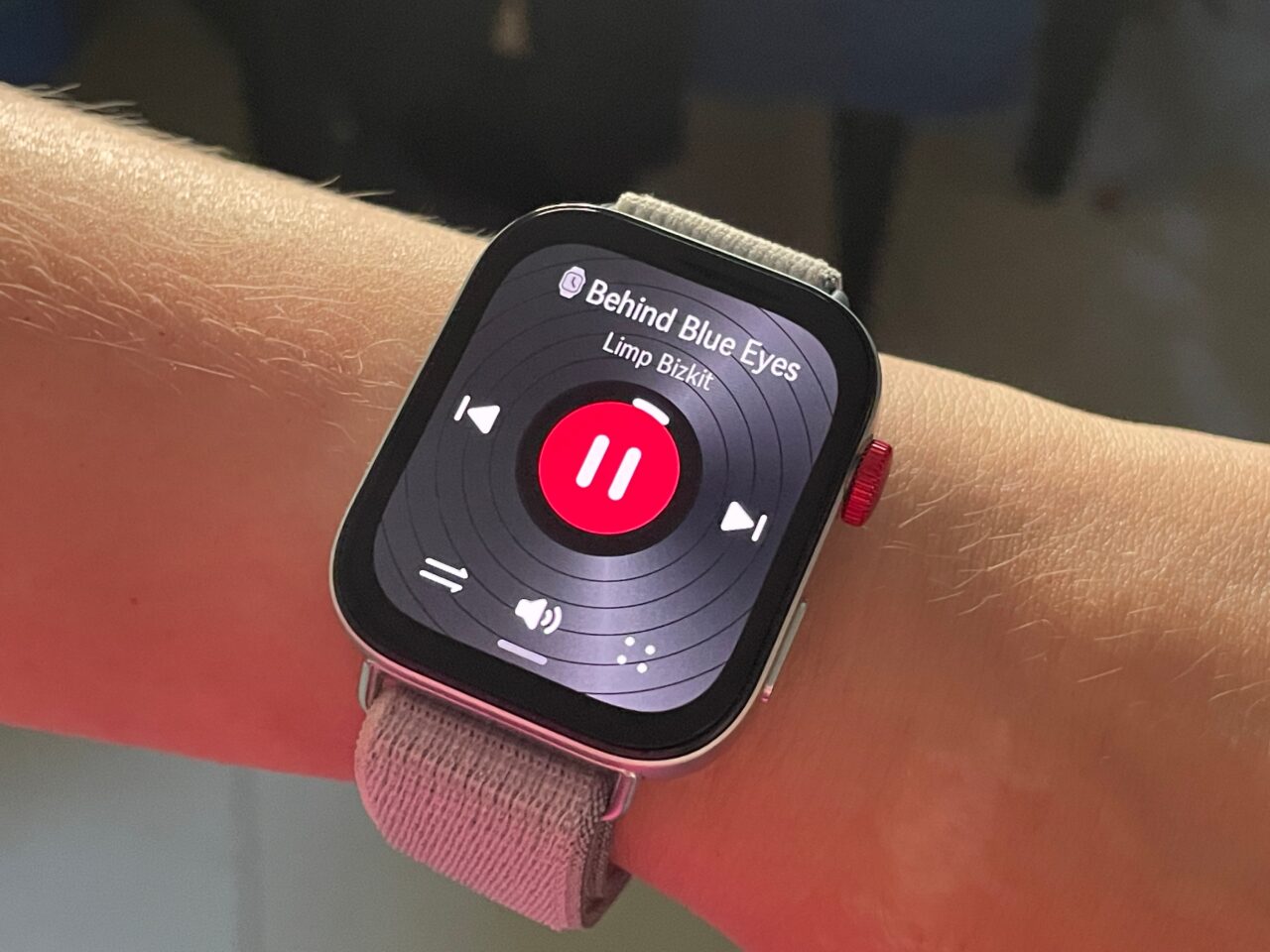 Zegarek smartwatch na ręce wyświetlający odtwarzacz muzyki z utworem "Behind Blue Eyes" zespołu Limp Bizkit.