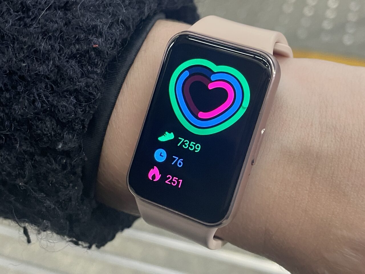 Inteligentny zegarek na nadgarstku pokazujący statystyki aktywności z kolorowym wykresem w kształcie serca.