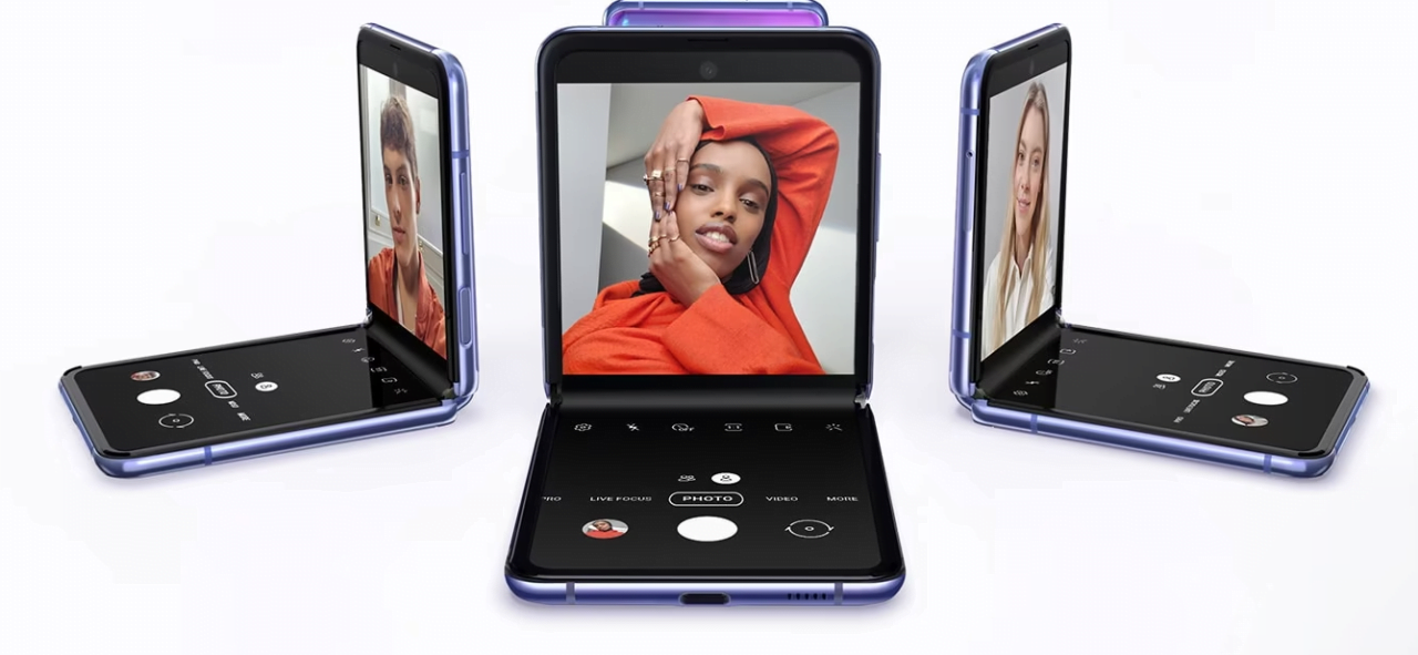 Trzy fioletowe, składane smartfony w trybie fotografowania z widocznymi różnymi osobami na ekranach.